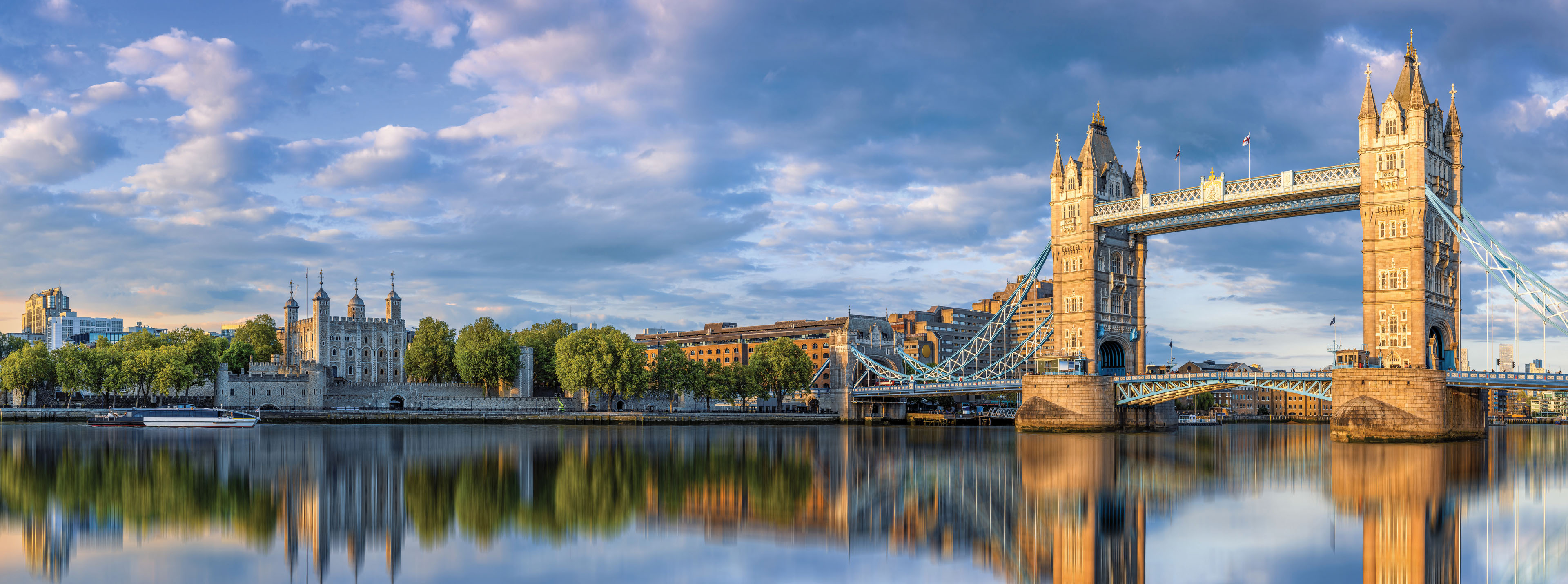 Tower Bridge and the historic Tower of London reflecting on the River Thames in London, England